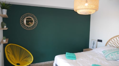 Modern bedroom at Ty Pals villa in Pals with green accent wall, yellow chair, white bed, and natural lighting