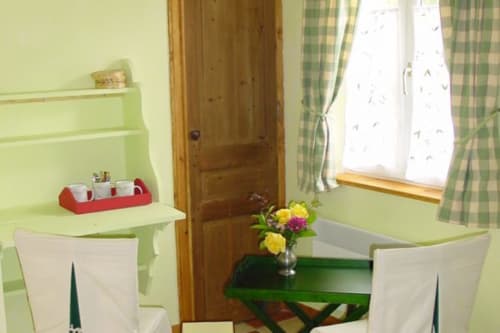 Bright green bedroom with desk, flowers, and window at Au Petit Tambour D'Autingues B&B in Autingues