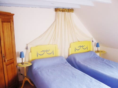 Twin beds with yellow headboards and cream canopy in Ninon room at Au Petit Tambour D'Autingues B&B, Autingues