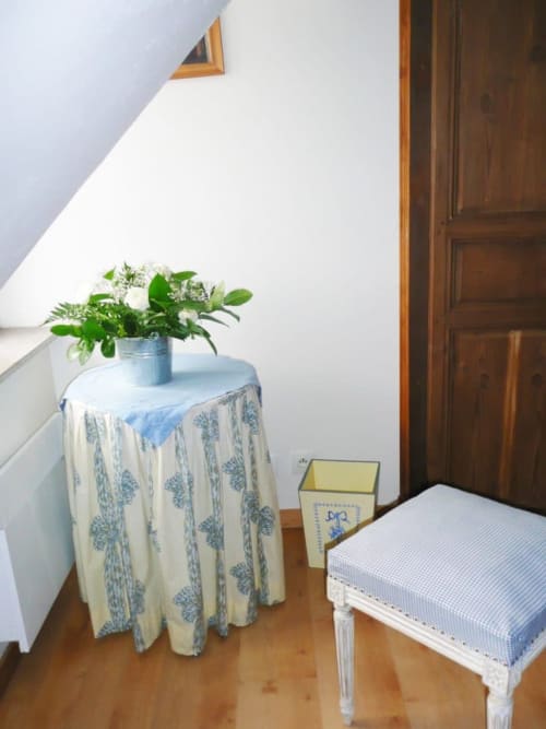 Cozy bedroom at Au Petit Tambour D'Autingues with floral table, white chair, and fresh flowers in Autingues, France