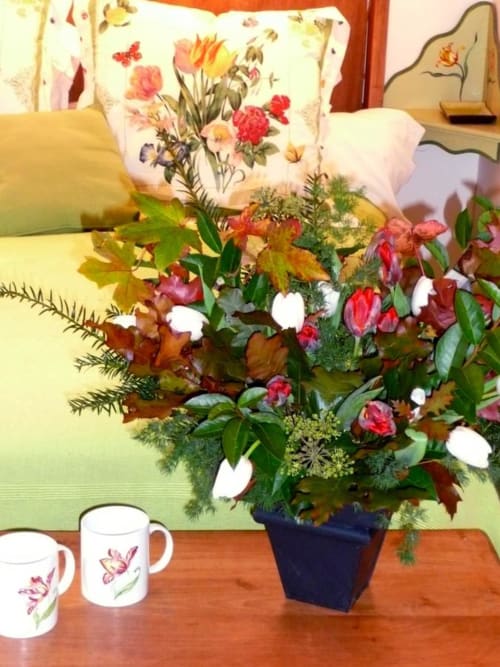 Vibrant floral arrangement with pink and white flowers in dark vase, displayed in Flandre Room at Au Petit Tambour