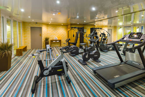 Modern fitness center at Hotel Residence Europe & Spa in Clichy with treadmills, stationary bikes, and exercise equipment