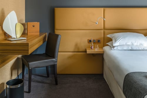 Modern hotel bedroom at Residence Europe & Spa in Clichy with mustard headboard and wooden desk