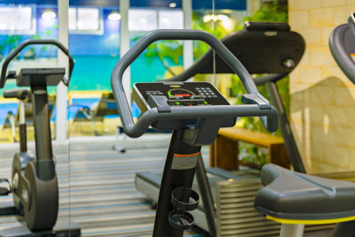 Vélos d'appartement modernes au centre de fitness de l'Hôtel Residence Europe & Spa avec vue sur la piscine à Clichy