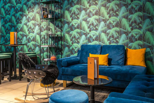 Modern lounge at Hotel Residence Europe & Spa with tropical wallpaper, blue velvet sofa, orange accents