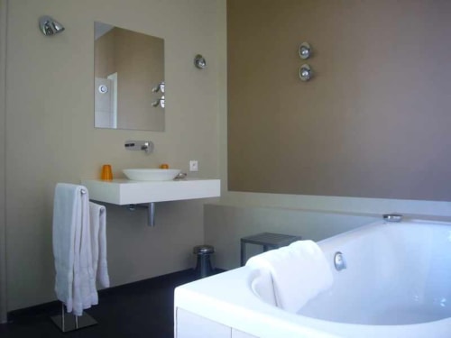 Suite de salle de bain moderne au Jardin De Beauvoir Lyon avec baignoire îlot, lavabo suspendu et miroir