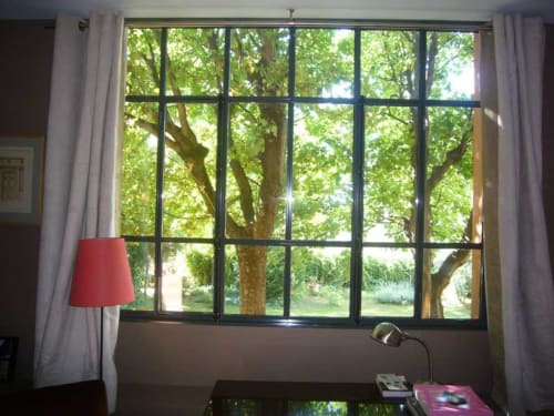 Grande fenêtre donnant sur un jardin verdoyant à Le Jardin De Beauvoir, suite Lyon BnB avec lampe de bureau et abat-jour rouge