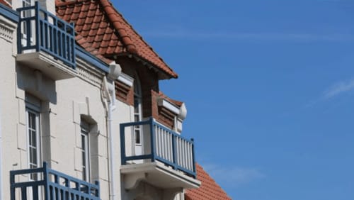 Façade de la maison d'hôtes Au Petit Tambour D'Autingues avec toit en tuiles terracotta et balcons bleus en France