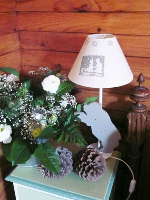 Bedside lamp with white shade and floral arrangement on turquoise nightstand in Edelweiss Room at Au Petit Tambour