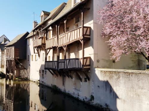Bâtiment à colombages historique avec arbre en fleurs roses surplombant le canal à Montargis, Gîte La Maison Virginie