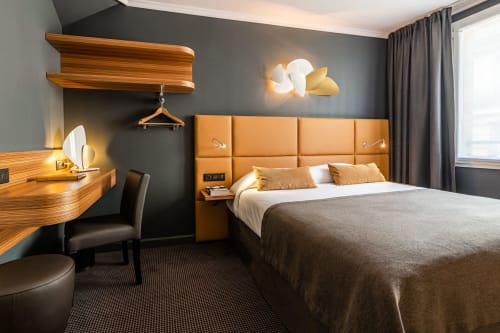 Comfort Room at Hotel Residence Europe & Spa in Clichy with orange headboard, wooden desk, and modern gray walls