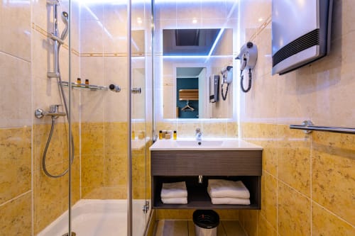 Modern bathroom in Comfort Room at Hotel Residence Europe & Spa, Clichy, with glass shower, vanity sink, and heated mirror.