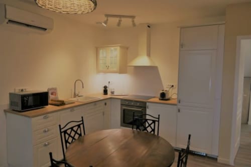 Cuisine et salle à manger modernes de l'appartement La Maison Virginie à Montargis avec armoires blanches et comptoirs en bois