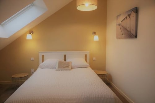 Chambre lumineuse à la maison d'hôtes La Maison Virginie à Montargis avec lit blanc, murs jaunes, luminaires suspendus et boiseries