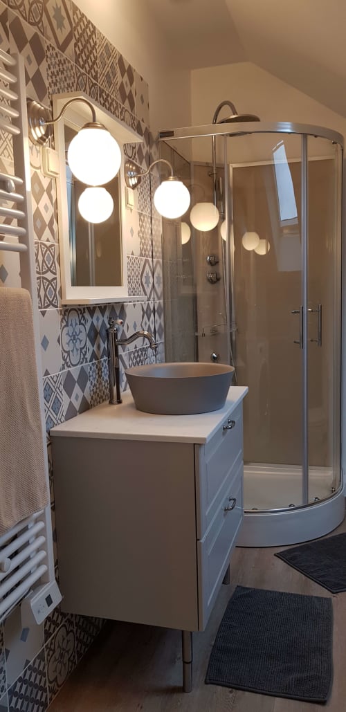 Salle de bain moderne de La Maison Virginie à Montargis avec vasque ronde, miroir circulaire, carrelage géométrique et design épuré