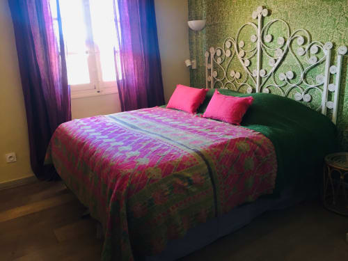 Vibrant bedroom at Saint Martin villa, Ollioules, with ornate headboard, pink bedding, and purple curtains overlooking