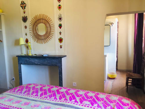 Bright yellow bedroom at Saint Martin villa, Ollioules, with pink patterned bedding, sunburst mirror, and decorative heart