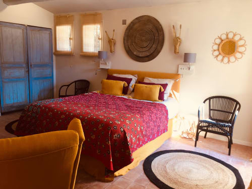 Sunny bedroom at Le Mas Saint Martin villa in Ollioules with red patterned bed, wicker décor, and mountain views