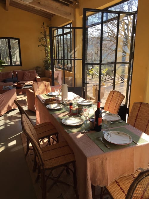 Sunny dining room at Saint Martin B&B in Ollioules with table set for meal, wicker chairs, and terrace views