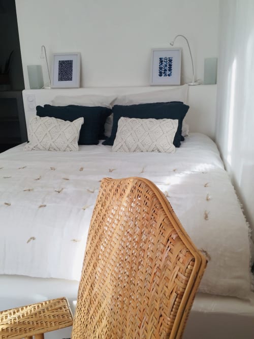Bright bedroom at Saint Martin B&B in Ollioules with white bedding, black pillows, woven chair, and blue artwork on shelf
