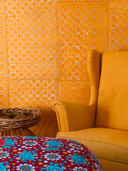 Yellow armchair against orange patterned wallpaper at Saint Martin B&B, Ollioules