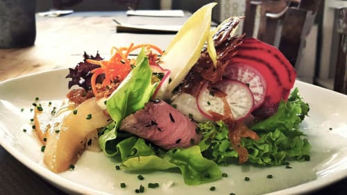 Plato gourmet en Ty Pals B&B de Pals con ternera sellada, vegetales frescos y microbrotes sobre plato blanco