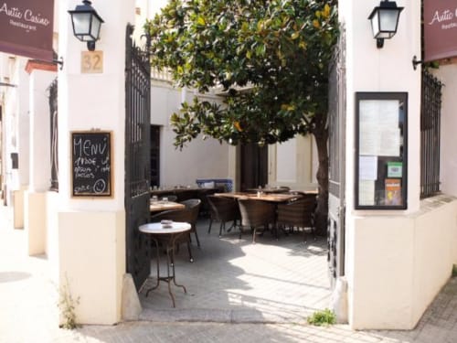 Encantadora zona de comedor en patio de la casa rural Ty Pals en Pals, España con limonero y puertas negras