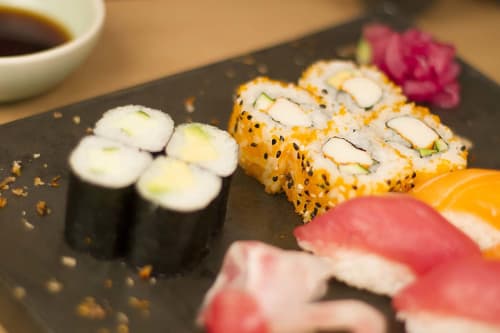 Variedad de rollos de sushi y nigiri en plato negro en el alojamiento Ty Pals B&B, Pals España con salsa de soja