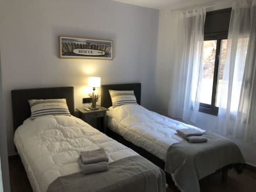 Twin beds with black headboards in bright bedroom at Ty Pals villa, Pals, Spain with sea views and sheer curtains