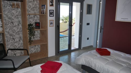 Modern villa bedroom at Ty Pals in Pals with two beds, sea view through glass doors, pool access, and contemporary decor