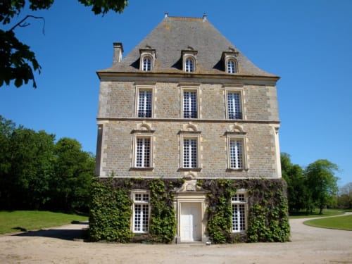 Château en pierre à toit mansardé et lierre grimpant à Tocqueville, France, entouré de verdoyants jardins