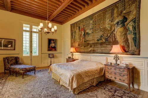 Chambre élégante du Château d'Alexis de Tocqueville avec plafond à poutres apparentes, tapisserie classique et mobilier d'époque.