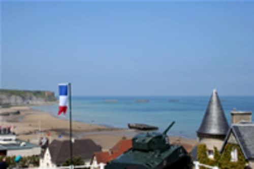 Drapeau français surplombant la plage de Normandie depuis les Gîtes Les Rainettes en Vienne-en-Bessin avec vue sur le village côtier