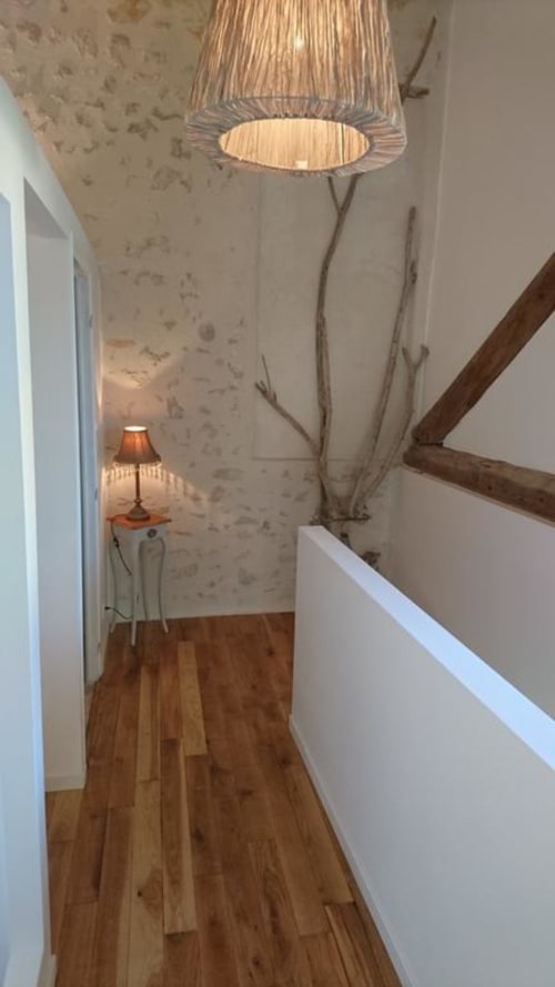 Couloir étroit du gîte Mas des Artistes avec parquet, suspension, branches décoratives et lampadaire