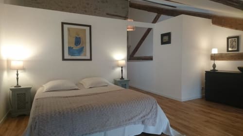 Chambre lumineuse du gîte Mazet 2 aux Mas des Artistes, Mouriès : lit queen-size, poutres apparentes, lampes de chevet et vue sur le jardin