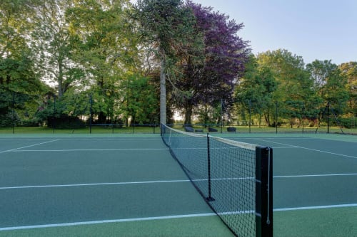 Tennis courts at Château d'Alexis de Tocqueville with tree-lined grounds in Normandy