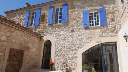 Mas des Artistes stone cottage in Mouriès with blue shutters and arched doorway, welcoming entrance to French countryside B&B