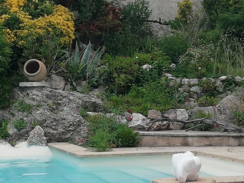 Turquoise pool with white sculpture at Mas des Artistes guesthouse in Mouriès, surrounded by terracotta pots and lush