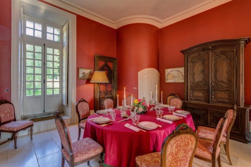 Elegant dining room at Château d'Alexis de Tocqueville with red walls, round table with fuchsia tablecloth, and ornate wooden