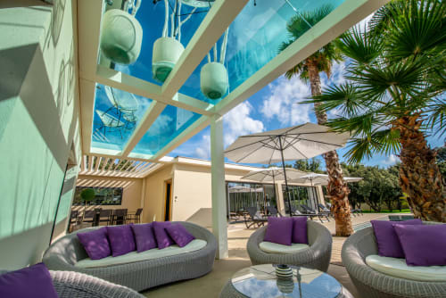 Terrasse luxueuse de la villa La Maison D'ambrine à Chamaret avec mobilier moderne, palmiers et vue sur la piscine