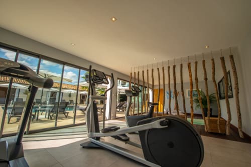 Salle de sport moderne avec vélos d'exercice surplombant la piscine à la villa La Maison D'ambrine à Chamaret