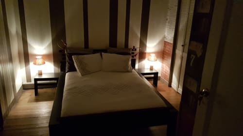 Chambre élégante de la Maison d'hôtes L'escale Marine à La Rochelle avec lit à baldaquin noir, linge crème et éclairage ambiant