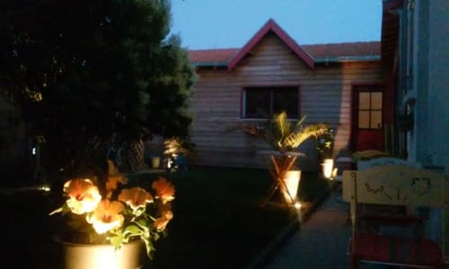 L'escale Marine BnB à La Rochelle en soirée, façade en bois illuminée et fleurs du jardin