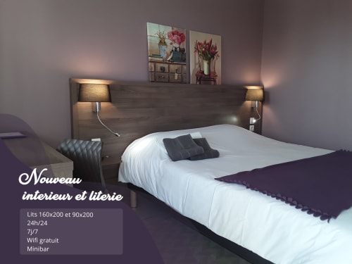 Chambre moderne du Relais Motel de Maisonnay avec lit double, tête de lit en bois, lampes de chevet et décoration florale