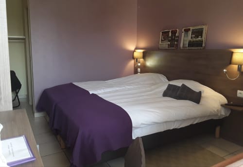 Chambre moderne du Relais Motel de Maisonnay avec lit double, accents violets, lampes de chevet et œuvres murales