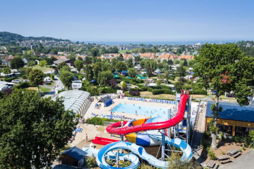 Parque acuático del hotel Les Cabines en Houlgate, Francia con piscinas, toboganes rojos y área residencial