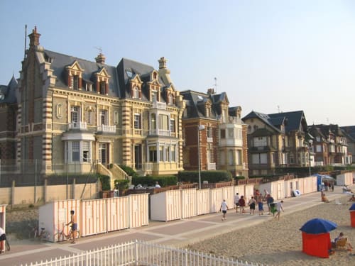 Hotel Les Cabines en Houlgate con arquitectura victoriana, cabinas de playa y playa arenosa con visitantes