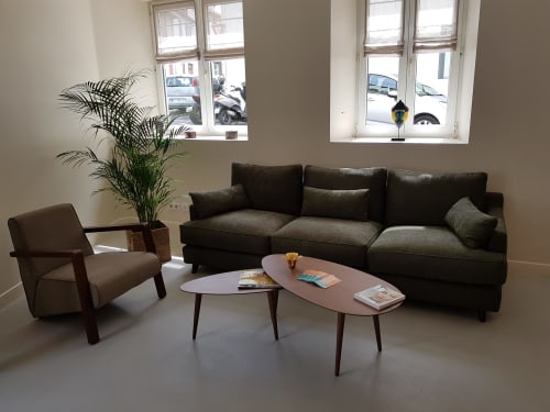 Modern lounge at Hotel Au Bon Coin, Biarritz featuring dark sofa, armchair, and wooden coffee table with plants