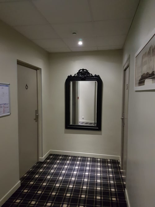 Hallway at Hotel Au Bon Coin Biarritz with black ornate mirror, plaid flooring, and cream walls