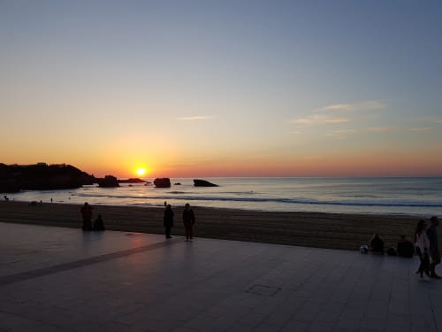 Sunset view from Hotel Au Bon Coin's beachfront terrace in Biarritz with ocean waves and golden sky